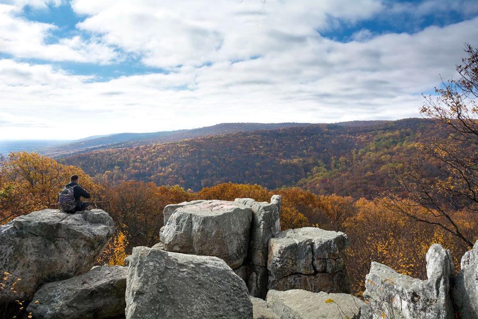 A rock formation in the foreground with forested mountains in the background