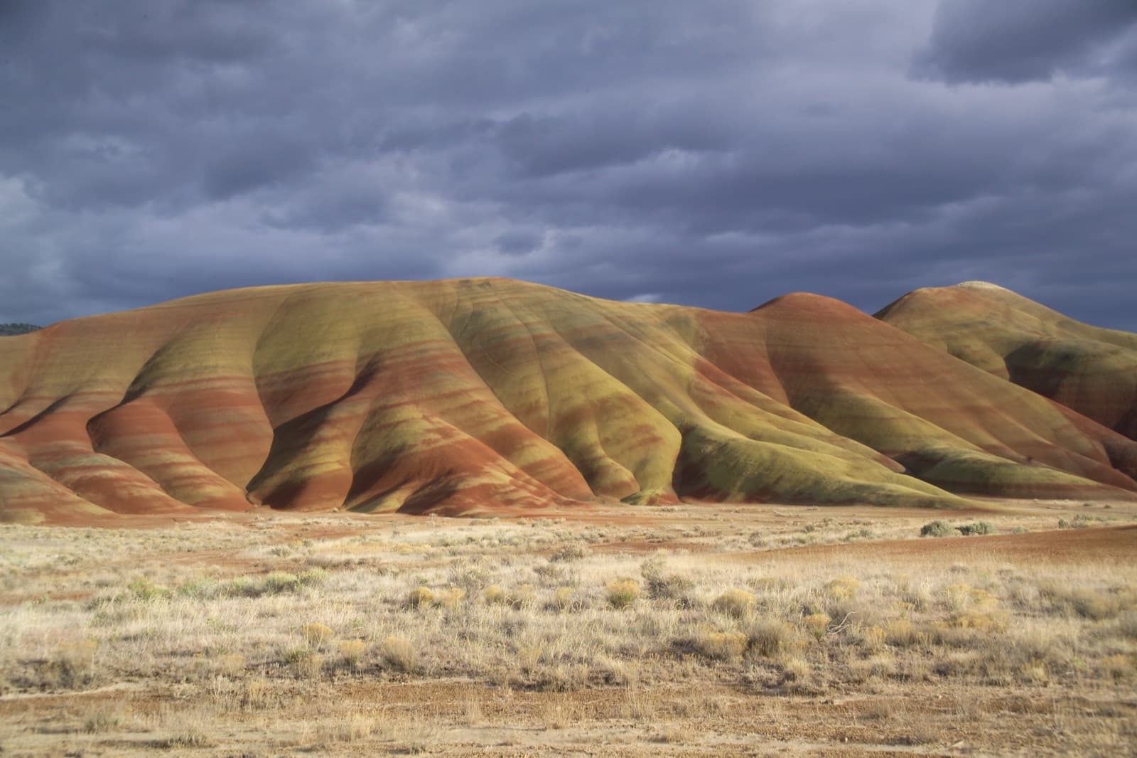 The banded, rounded Painted Hills under a stormy sky