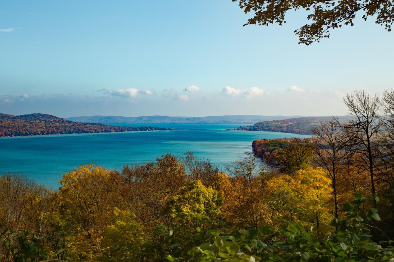 Yellow and orange autumn trees above two long blue lakes, with wooded hills beyond
