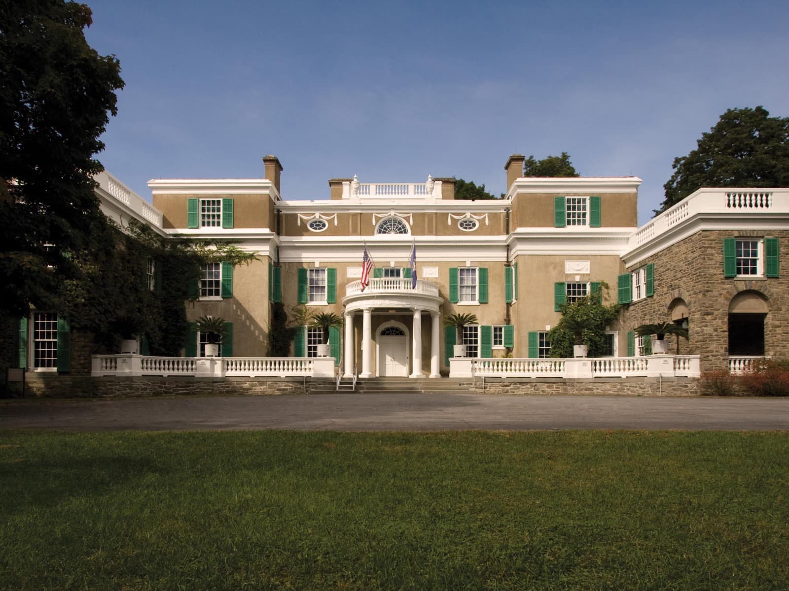 A stucco and fieldstone house with white trim and circular portico