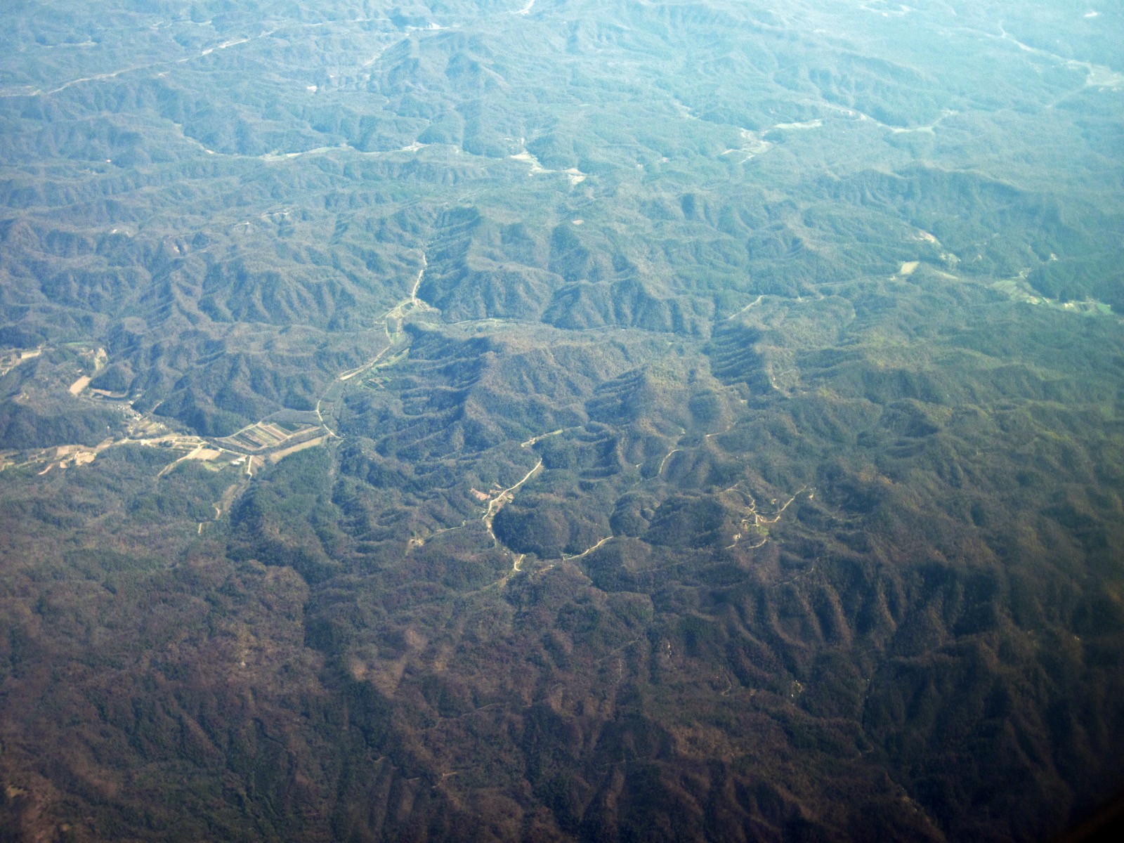 Hazy aerial view of rows of forested ridges and valleys