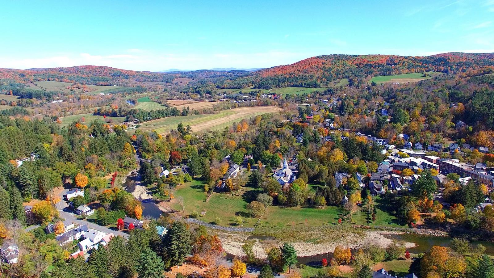 Aerial view of Woodstock village, its green and the Ottauquechee River with fall color on the hills behind